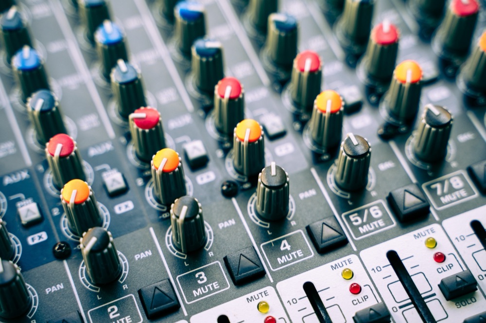 A sound mixing desk with rows of coloured control knobs